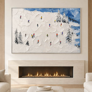 Hand-painted snowy mountain canvas with colorful skiers and pine trees, displayed beside or above a fireplace in a silver frame.