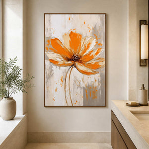 Wood framed orange flower painting beside a beige bathroom vanity and a sunlit window.