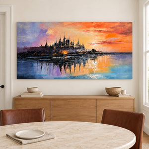 A distant castle reflected in water beneath an orange sunset without an outer frame, displayed above a dining table.