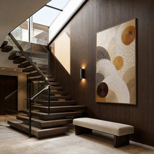 Layered circles in gold, brown, and ivory wall art in a contemporary stair hall.