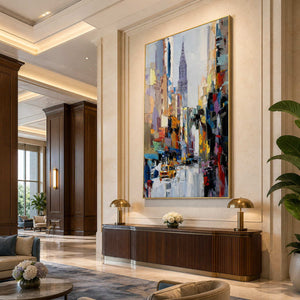 Gold framed colorful cityscape above a curved hotel lobby console with paired lamps.