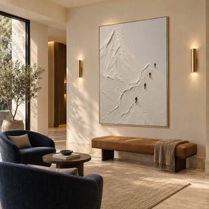 Four climbers ascending sculpted white mountain ridges in a vertical composition, displayed in a hotel lounge in a gold frame.