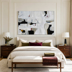 White framed abstract artwork above a cream bed with burgundy and olive cushions.