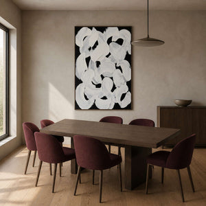 Wood framed white abstract loops above a dining table with burgundy chairs.