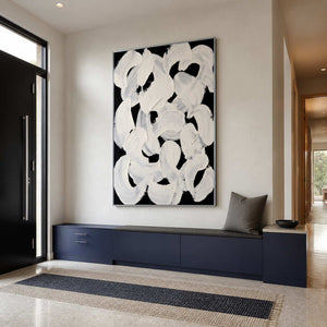 Silver framed white loops above navy entryway cabinets beside a black front door.