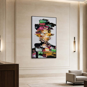 Black framed multicolored portrait on a pale stone wall beside a hotel lounge chair.