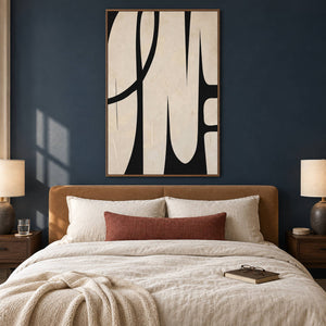 Cream and black abstract painting with elongated forms and a sweeping arc in a brown wood frame in a bedroom.