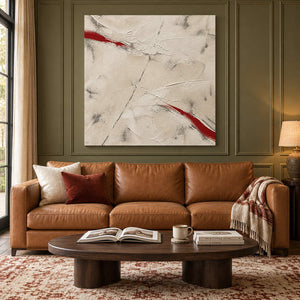Ivory textured abstract painting with red diagonal strokes without an outer frame in a living room.