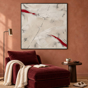Ivory textured abstract painting with red diagonal strokes in a black frame in a lounge.