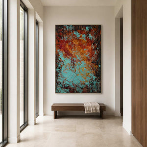 Silver framed rust and turquoise abstract painting above a bench in a bright hallway.