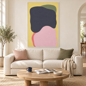Yellow abstract painting with charcoal, blush, olive, and coral shapes in a white frame in a living room.