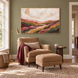 Dreaming of the Hills in a gold frame above a tan armchair with a burgundy throw and matching footstool.