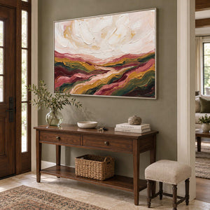 Dreaming of the Hills in a silver frame above a wood console with a glass vase of branches and a woven basket.