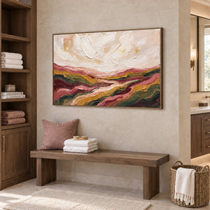 Dreaming of the Hills in a wood frame above a bench with blush cushions and folded towels in a bathroom dry area.