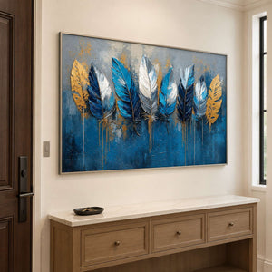 Blue, white and gold feathers against a deep blue and gray background in a silver frame, displayed above an entryway console.