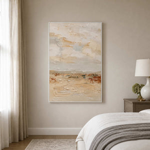 White framed pale textured landscape painting beside a bed in a softly lit bedroom.