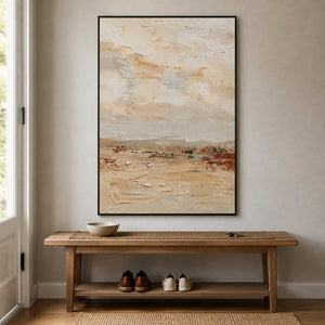 Black framed cream landscape painting above a wooden bench in a bright entryway.