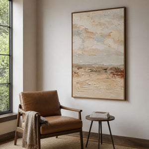 Wood framed textured landscape painting beside a leather chair in a reading corner.
