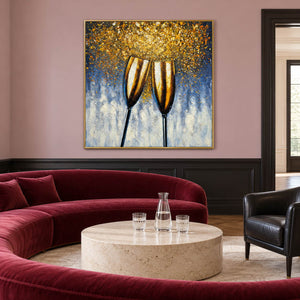 Artwork showing two golden champagne flutes leaning together beneath gold-colored speckles on blue gray in a living room above seating, with a gold-colored frame.