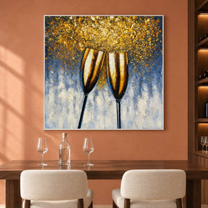 Above a tasting table with glasses, an artwork with a white frame shows two golden champagne flutes leaning together beneath gold-colored speckles on blue gray.