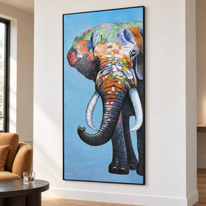 Artwork showing a front-facing elephant with an upcurled trunk, pale tusks and colored blocks on blue in a seating area, with a black frame.