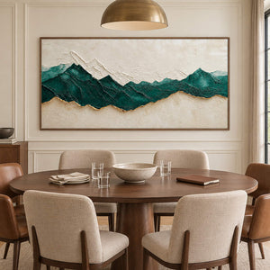 Hand-painted panoramic mountain wall art in emerald green, ivory, and gold, displayed in a dining room in a brown wood frame.