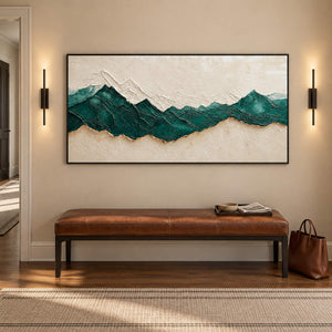 Hand-painted panoramic mountain wall art in emerald green, ivory, and gold, displayed in a hallway in a black frame.