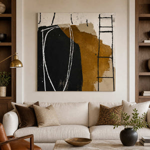 Frameless black and ochre abstract painting above a cream sofa between wooden shelves.