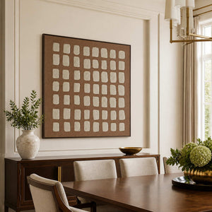 Black framed cream grid artwork above a dining room sideboard beside a wooden table.