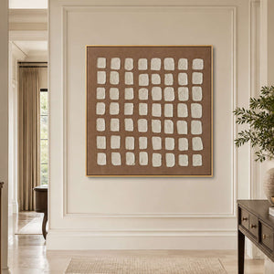 Gold framed cream grid artwork on a hallway wall near an open doorway.