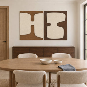 Two panels of complementary ivory organic forms on brown grounds without outer frames, displayed above a dining table.