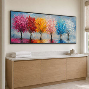 A row of colorful trees reflected beneath a pale sky in a black frame, displayed in a bathroom dry area.
