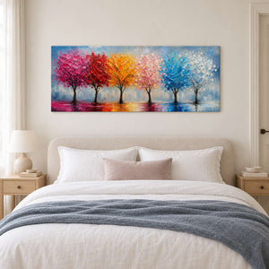 A row of colorful trees reflected beneath a pale sky without an outer frame, displayed above a bed.