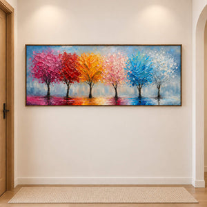 A row of colorful trees reflected beneath a pale sky in a brown wood frame, displayed in a hallway.