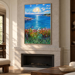 Above a fireplace, an artwork with a silver-colored frame shows a sunlit blue sea between low shores with colorful flowers in the foreground.