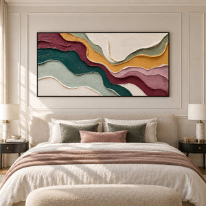 Wide flowing abstract above a beige bed with muted pink throw and green pillows.