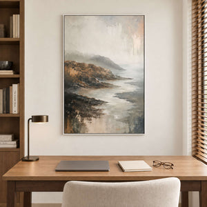A rocky coast receding into soft gray mist in a white frame, displayed in a home office.
