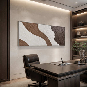 Silver-framed abstract wall art above a leather chair beside a dark wooden desk.