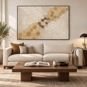 Ivory relief painting with crossing bands of gold and cream circles in a black frame in a living room.