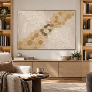 Ivory relief painting with crossing bands of gold and cream circles in a silver frame in a reading room.