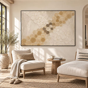 Ivory relief painting with crossing bands of gold and cream circles in a black frame in a sunlit seating area.