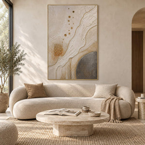 Ivory and gold relief painting with flowing ridges and textured circles in a gold frame in a living room.