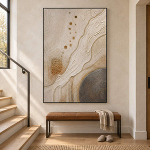 Ivory and gold relief painting with flowing ridges and textured circles in a black frame on a stair landing.