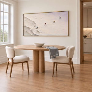 Four skiers crossing an open ivory-white slope in a gold frame, displayed above a dining table.