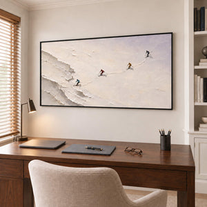 Four skiers crossing an open ivory-white slope in a black frame, displayed in a home office.