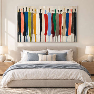 Colorful elongated figures displayed above a neutral upholstered bed with blue-gray bedding.