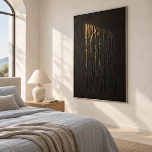 Hand-painted vertical abstract canvas with carved black ridges and gold relief, displayed in a bedroom in a silver frame.