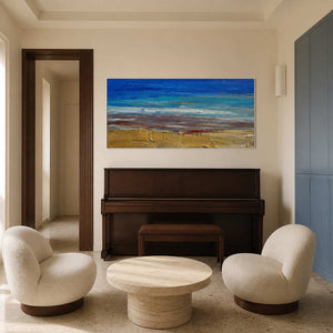 Blue coastal wall art displayed above a dark wood piano.