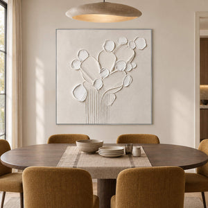 Sculptural warm white petals and leaves raised from a monochrome canvas, displayed in a dining room in a silver frame.
