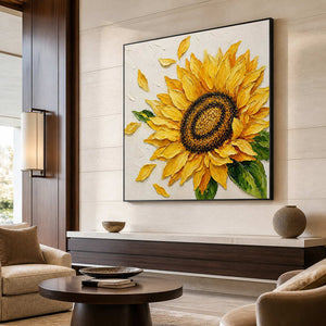 Black-framed sunflower artwork on a pale stone wall above a low cabinet in a hotel seating area.